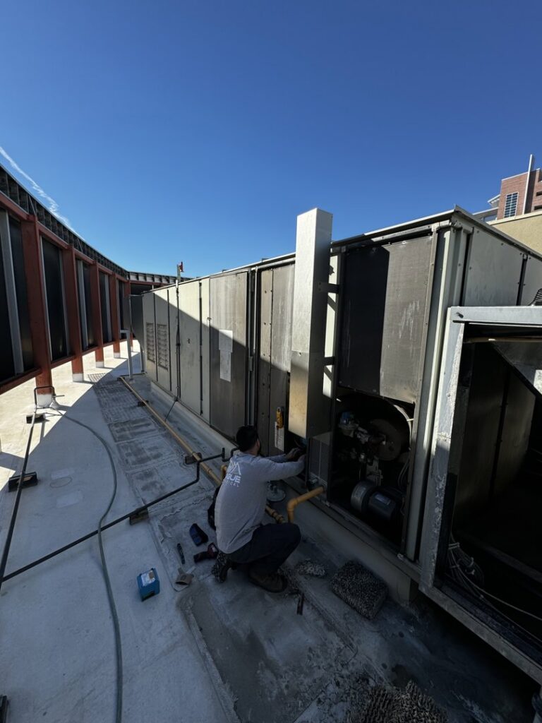 An HVAC technician repairing a commercial rooftop HVAC unit for Rogue Mechanical in Las Vegas, NV.