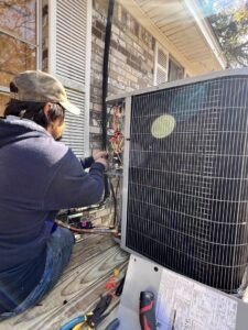An HVAC technician performing repairs and wiring on an outdoor condenser unit for Anderson Mechanical Inc. in Pascagoula, MS