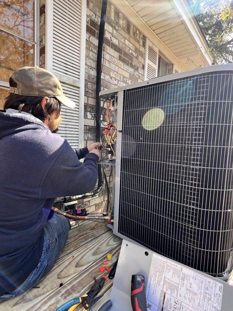 An HVAC technician performing repairs and wiring on an outdoor condenser unit for Anderson Mechanical Inc. in Pascagoula, MS