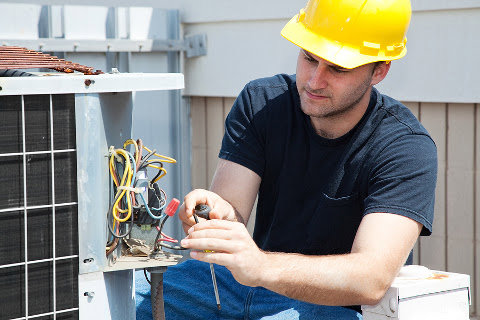 An HVAC technician repairing the electrical components of an outdoor condenser unit for R A Styron Heating & Air Conditioning, Inc. in Chesapeake, VA.
