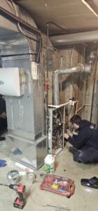 An Air Docs Inc. technician performing repairs on a residential furnace and ductwork in Vero Beach, FL
