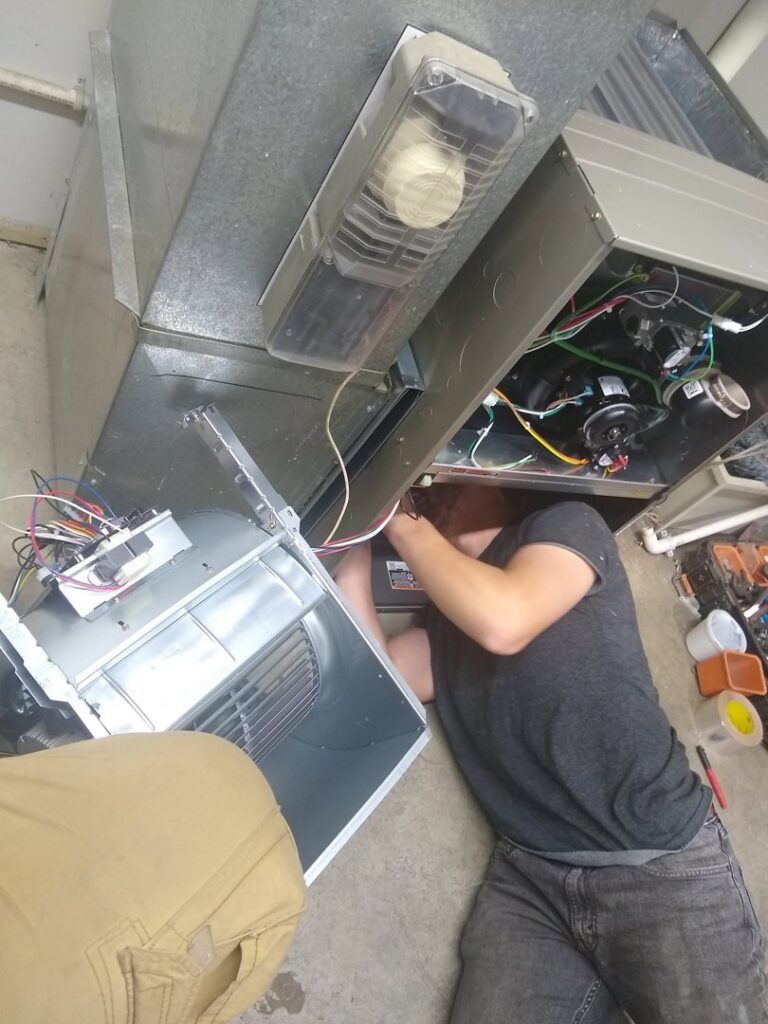 An HVAC technician from Wyles Heating & Air Conditioning Inc. repairing the blower section of a furnace in North Canton, OH.