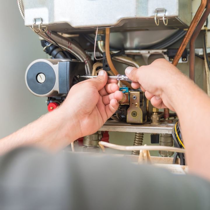 An HVAC technician performing repair work on a furnace or boiler for Cosmic HVAC in Chicago, IL.