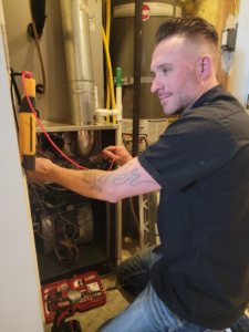An HVAC technician repairing a furnace with tools at a client's home for Carter HVAC & Service in Seagrove, NC.