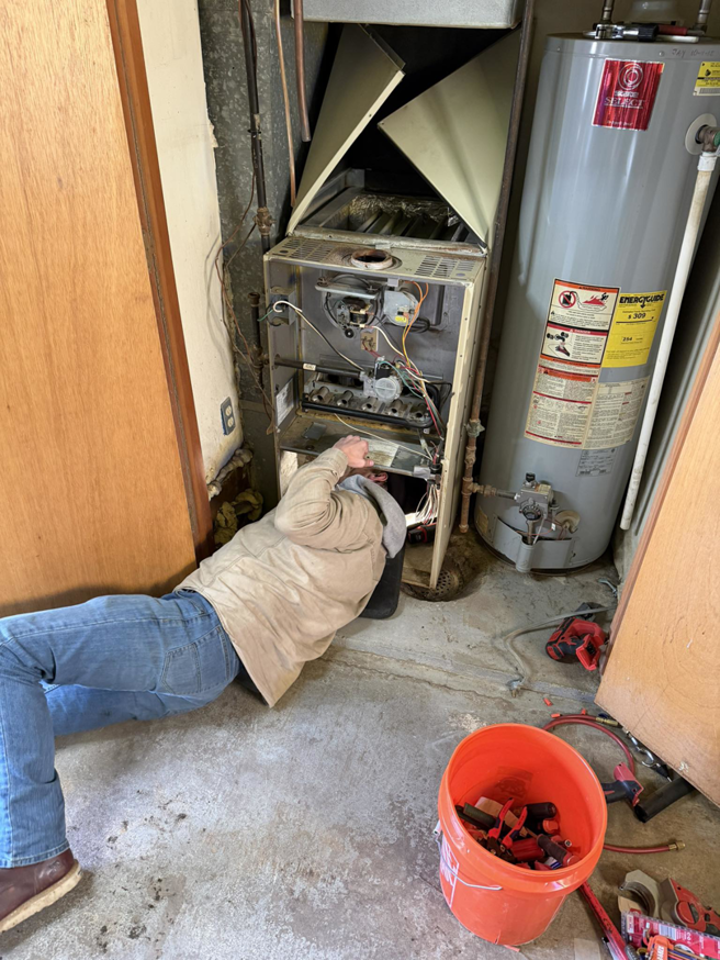 An HVAC technician repairing a furnace unit for Central Comfort Air in Miami, FL