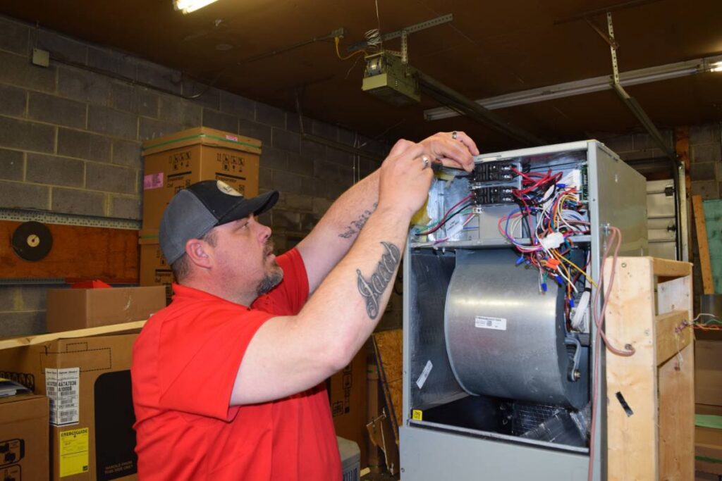 An HVAC technician from Family Heating & Air Conditioning repairing internal furnace components in Indianapolis, IN.
