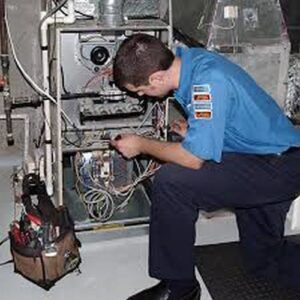 An HVAC technician repairing a furnace unit, connecting wires for Dan Deckard Hvac in Charlotte, NC