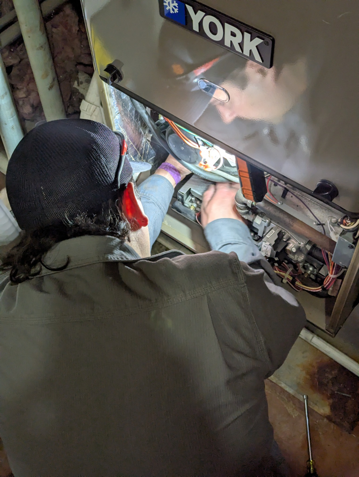 An HVAC technician repairing a York furnace, demonstrating expert service from Encode Corporation in Billings, MT.