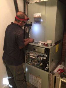 An HVAC technician repairing an indoor furnace unit for Fred's Heating And Cooling in Charlotte, NC