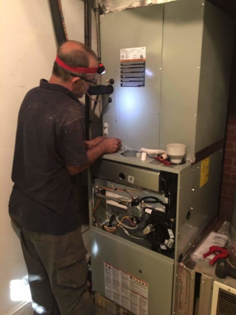 An HVAC technician repairing an indoor furnace unit for Fred's Heating And Cooling in Charlotte, NC