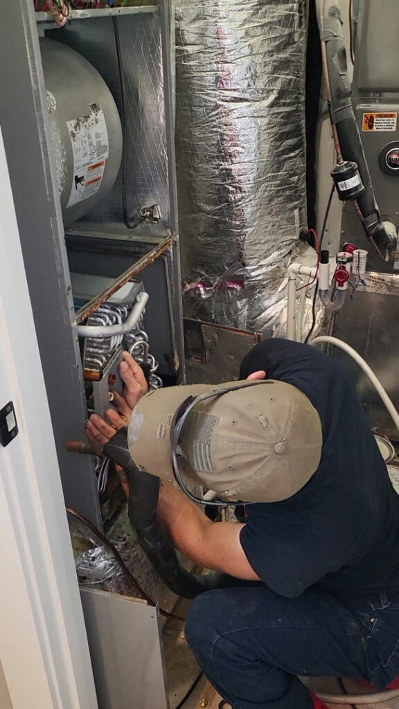 An HVAC technician performing repairs on an indoor furnace or air handler unit for Gouker's Best Air in Franklin, TN.
