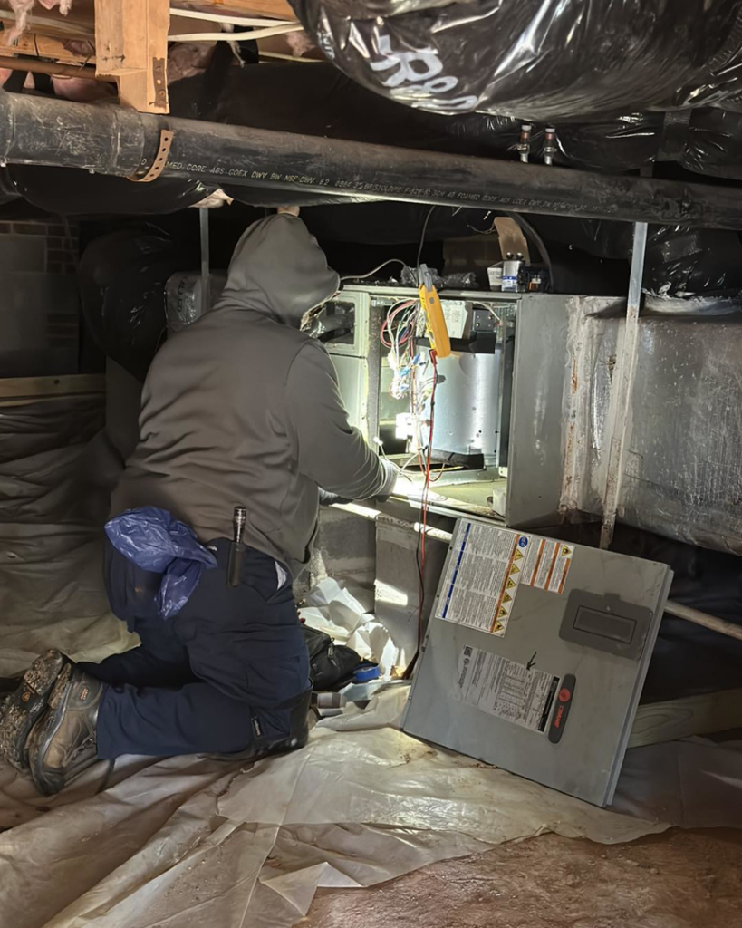 An Icy Hot Heating and Air Conditioning technician repairing an indoor furnace unit in Raleigh, NC.