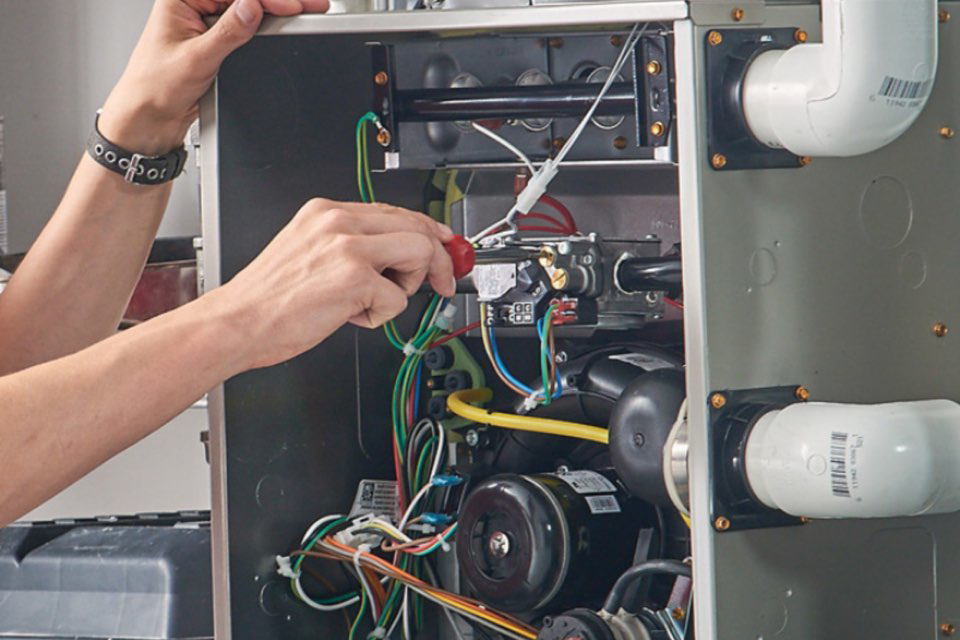 An HVAC technician repairing the internal components of a furnace at Missouri River Heating & Cooling in Mandan, ND.