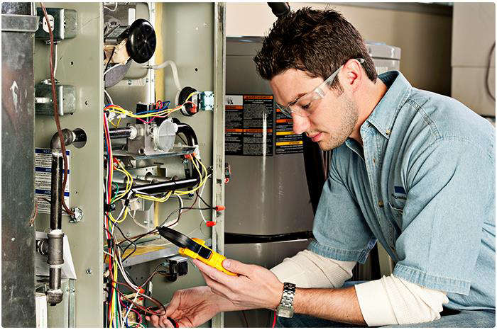 An HVAC technician repairing a furnace with a multimeter at Moss Creek HVAC Services in Colorado Springs, CO