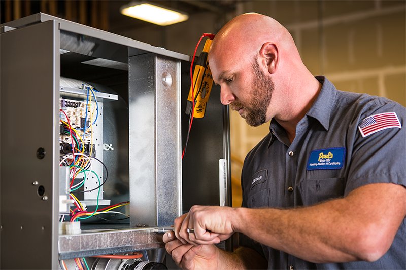 An HVAC technician repairing a furnace unit for Paul's Heating & Air Conditioning in Virginia Beach, VA.