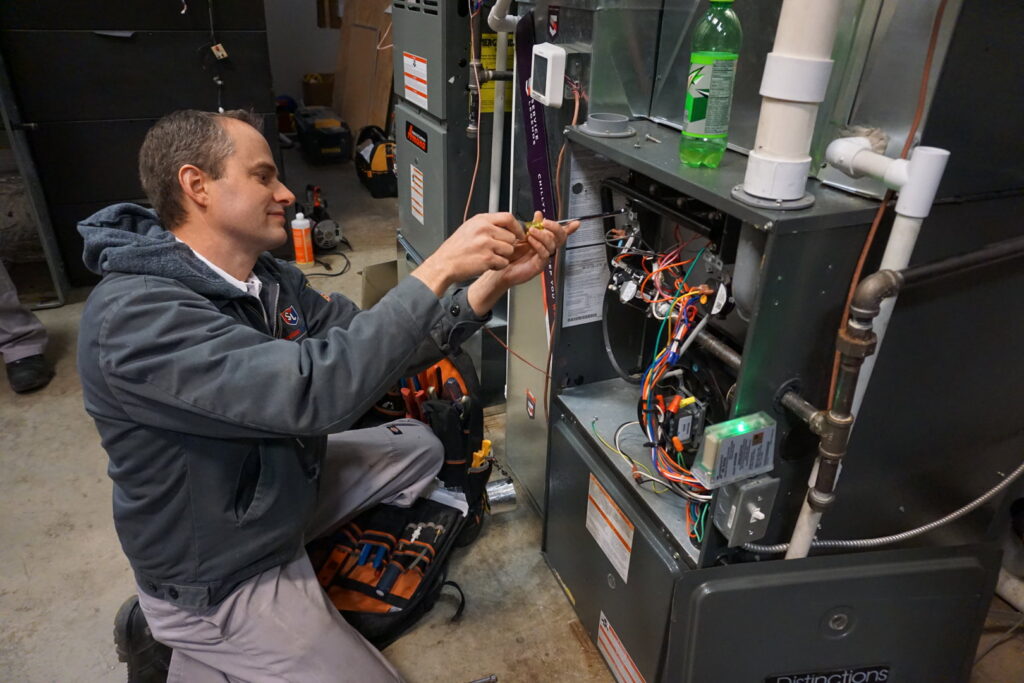 A Service Legends HVAC technician repairing an indoor furnace system in Des Moines, IA.