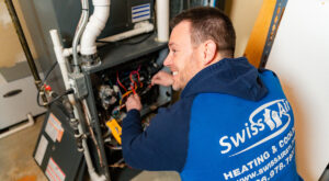 A skilled HVAC technician from Swiss Air Heating & Cooling performing repairs on a furnace in O'Fallon, MO.