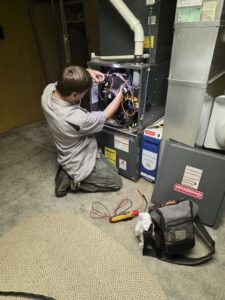 An HVAC technician repairing the internal components of a furnace system for Thrasher Service Corp in Des Moines, IA.