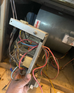 An HVAC technician repairing furnace wiring and controls for B & H Heating and Air Services LLC in Local City, ST.