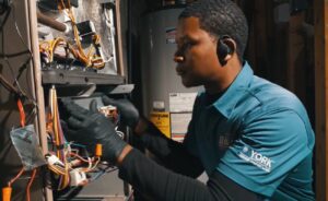 An HVAC technician repairing the wiring and components of a furnace at a client's home for Relief Heating and Cooling, LLC in Greensboro, NC.