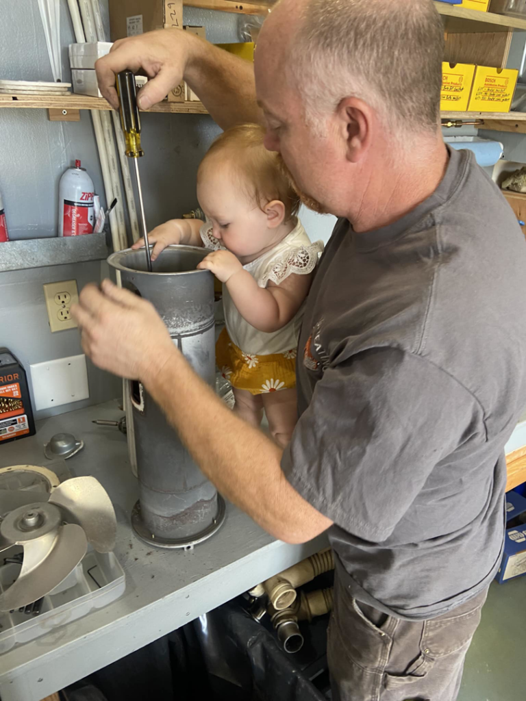 An HVAC technician from Vintage Heating LLC repairing a heating unit in Ketchikan, AK