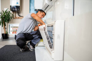 An HVAC technician repairing an indoor split air conditioning unit for Cosmic HVAC in Chicago, IL.
