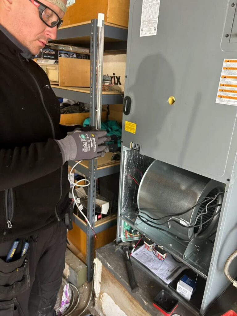 An HVAC technician from Fuse HVAC & Appliance Repair Boston repairing an indoor furnace unit in West Roxbury, MA.