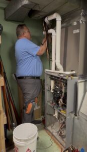 An HVAC technician repairing an indoor furnace or air handler unit for Wright Way Air in Streamwood, IL