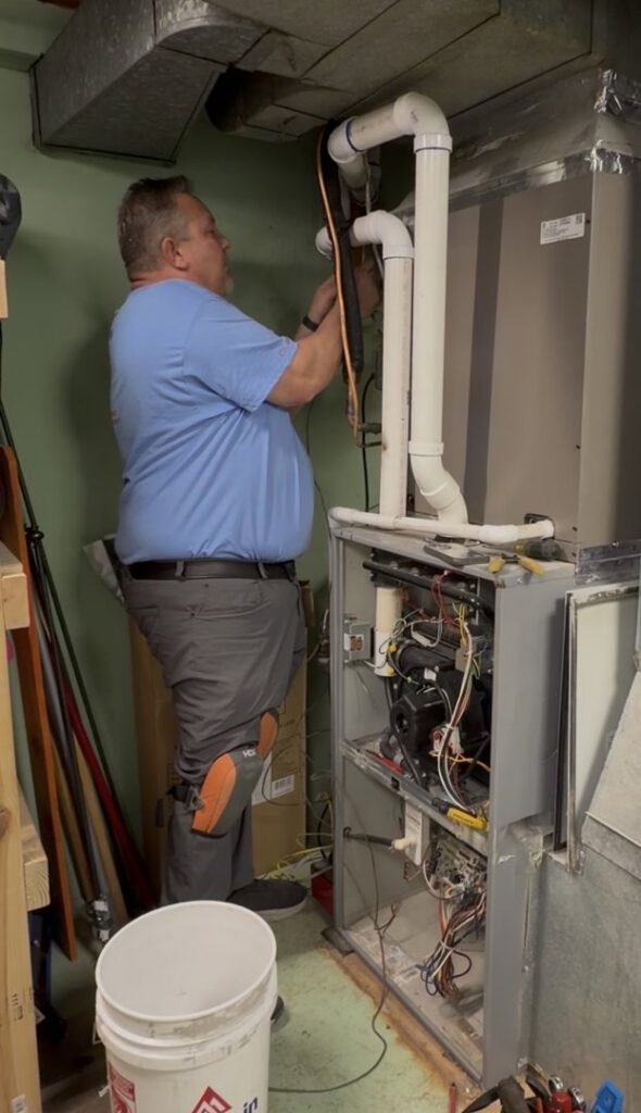 An HVAC technician repairing an indoor furnace or air handler unit for Wright Way Air in Streamwood, IL