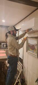 An HVAC technician repairing a wall-mounted mini-split AC unit for Desert Sage Heating and Cooling in Albuquerque, NM.