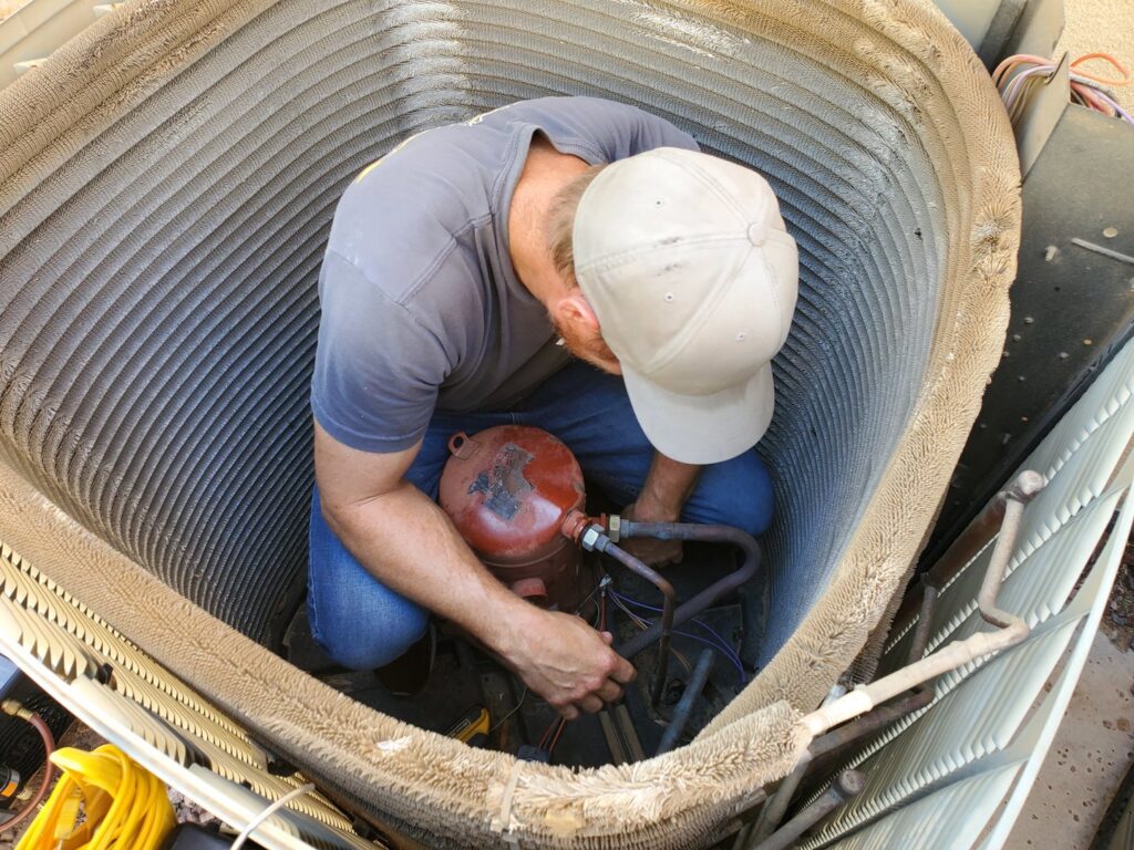 An HVAC technician from Arrow Pro Services repairing an outdoor air conditioning unit in Gilbert, AZ