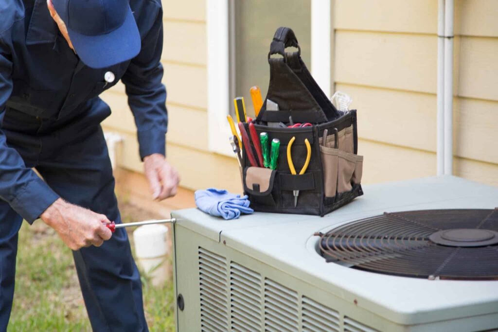 An HVAC technician repairing an outdoor air conditioning unit with tools nearby for Boykin Air Conditioning Services in Sumter, SC.