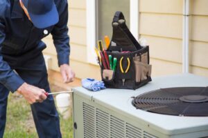 An HVAC technician repairing an outdoor air conditioning unit with tools nearby for Boykin Air Conditioning Services in Sumter, SC.