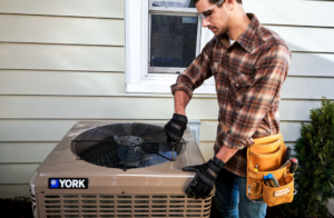 An HVAC technician repairing an outdoor air conditioning unit for Ocean State Mechanical Inc. in Coventry, RI.