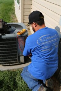 An R.J. Nelson Co technician repairing an outdoor air conditioning unit in Council Bluffs, IA.