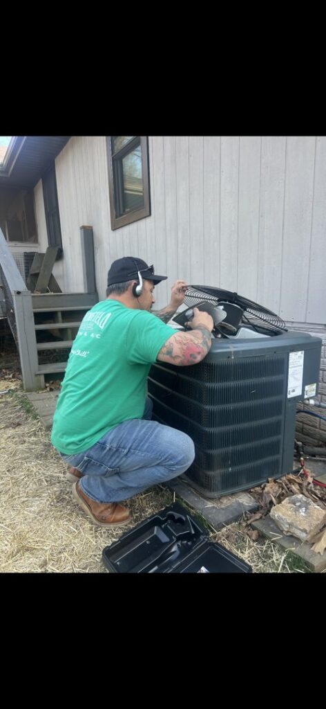 An HVAC technician from Springfield HVAC Company repairing an outdoor air conditioning unit in Springfield, MO.