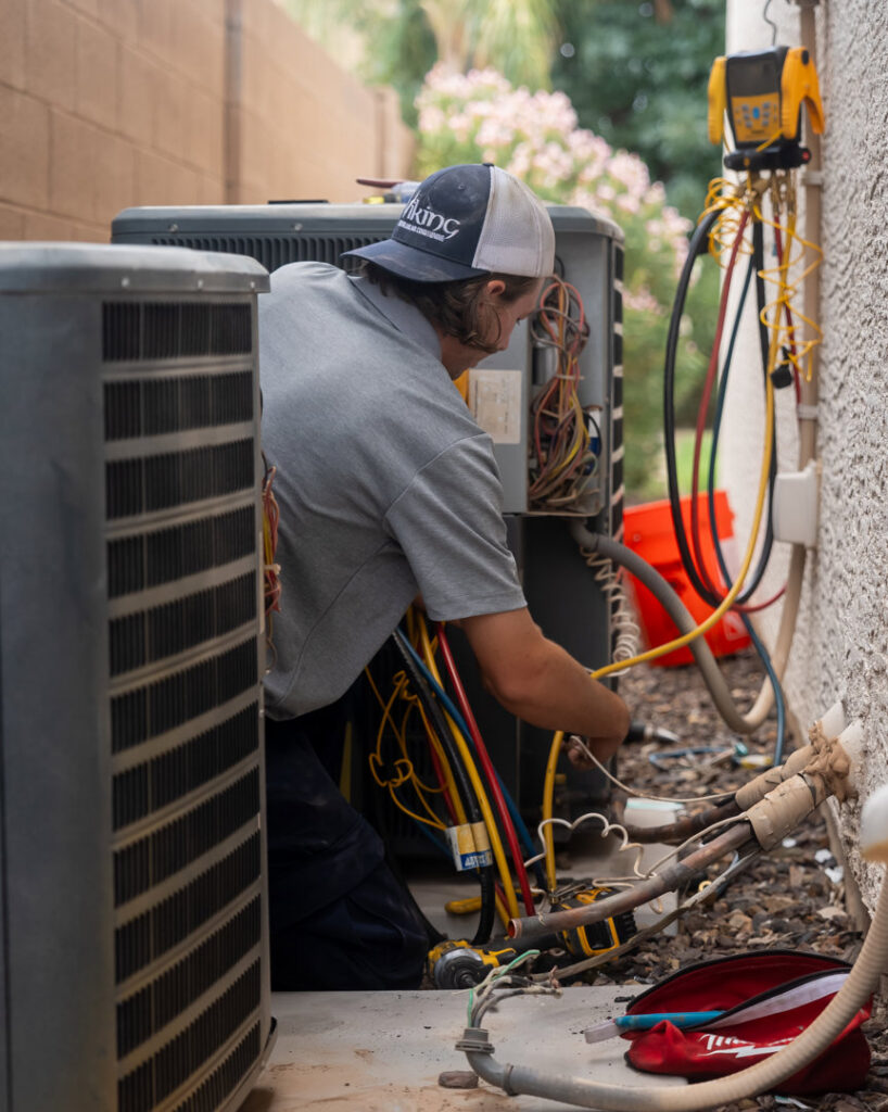 An HVAC technician repairing an outdoor AC unit for Viking Heating and Air Conditioning, LLC in Chandler, AZ