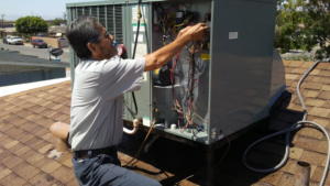 An HVAC technician repairing an outdoor AC unit on a rooftop for AC Phoenix LLC AC Repair & Service in Glendale, AZ.