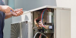 An HVAC technician repairing the internal components of an outdoor unit for Air Works of Alabama LLC in Mobile, AL.