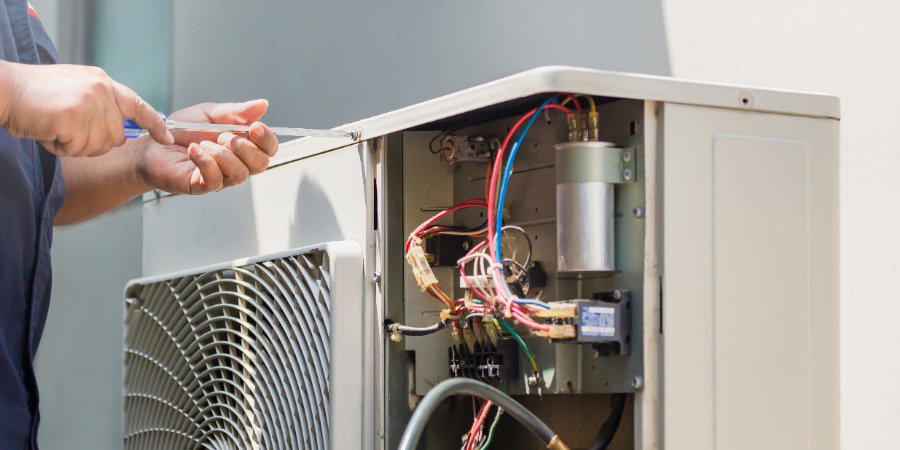 An HVAC technician repairing the internal components of an outdoor unit for Air Works of Alabama LLC in Mobile, AL.