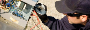 An HVAC technician repairing an outdoor unit, checking electrical connections for Bay Heating & Cooling Ltd in Annapolis, MD.