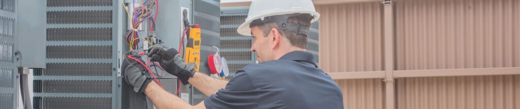 An HVAC technician from Bergmann Heating & Air Conditioning, LLC in Orem, UT, repairing an outdoor unit's electrical components