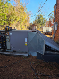 An HVAC technician from Coleman Services performing repair or maintenance on an outdoor HVAC unit in Columbia, SC, with internal components visible.