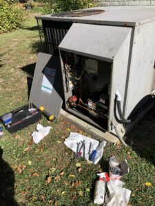 An HVAC technician performing repair or maintenance on an outdoor unit with tools laid out by Deon Arnold Heating & Air Conditioning in Fayetteville, NC