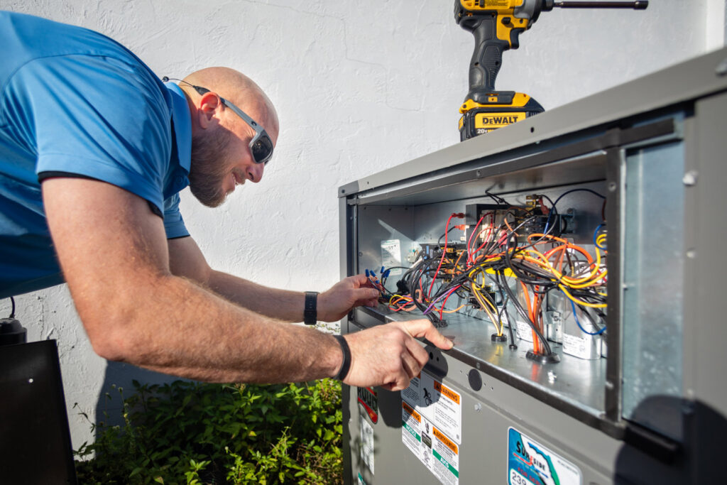 An HVAC technician repairing the electrical panel of an outdoor unit for Surfside Heating & Cooling in Cape Coral, FL.