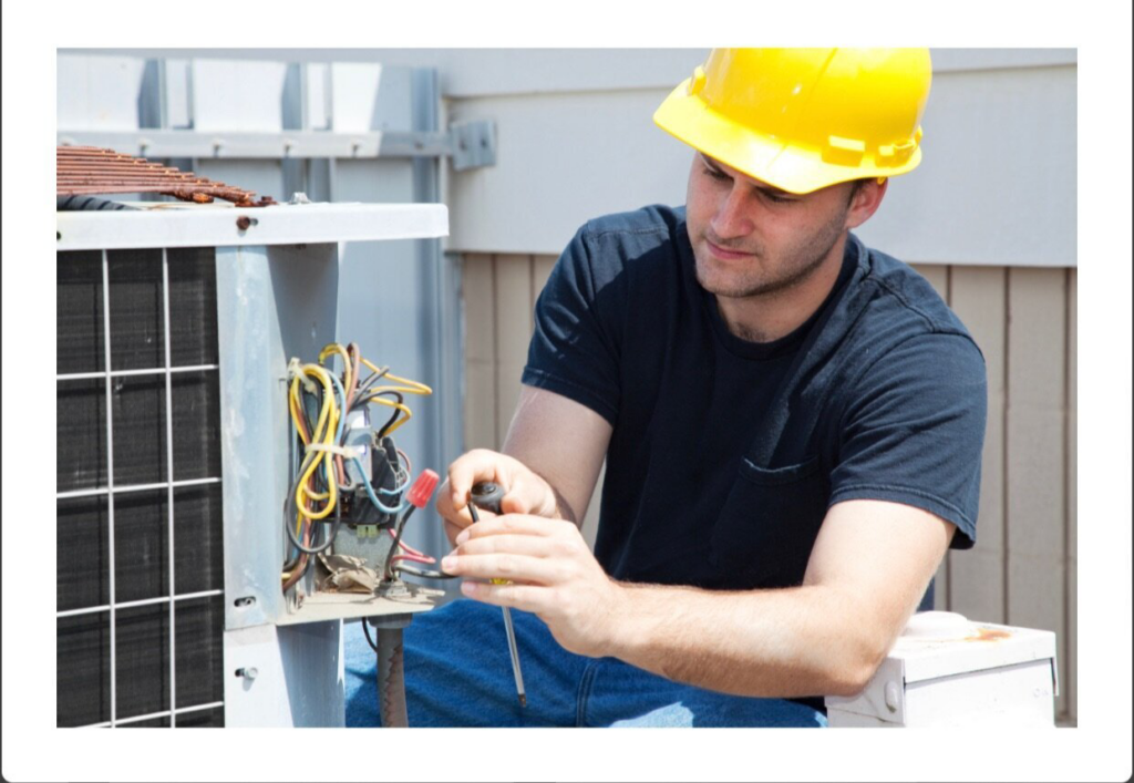 An HVAC technician in a hard hat repairing an outdoor air conditioning unit for HVAC Erie in Erie, PA.