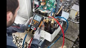 An HVAC technician repairing an outdoor unit with a digital manifold gauge for Luciano's Air Services in Durham, NC.