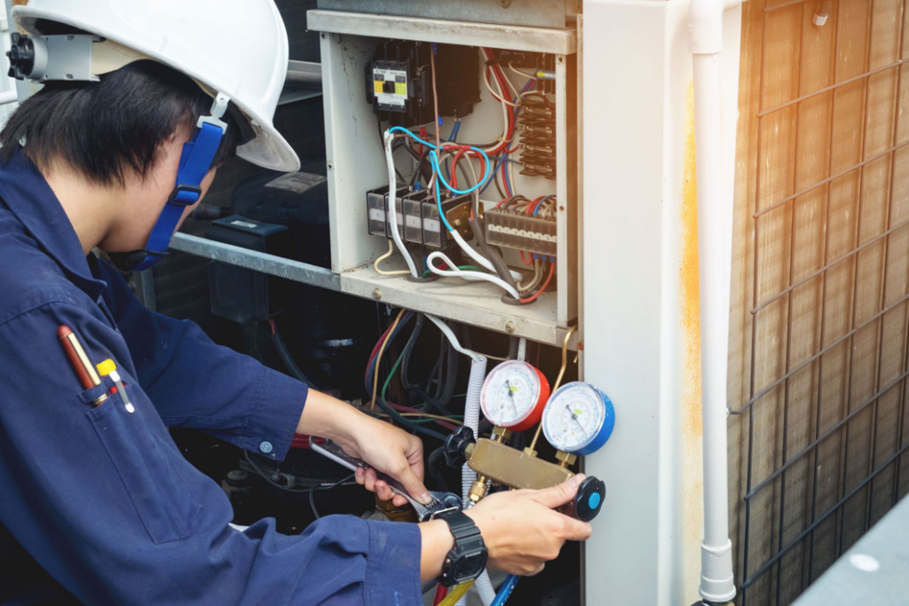 An HVAC technician repairing an outdoor unit with gauges for Malone Heat & Air, Inc. in Chattanooga, TN