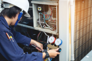 An HVAC technician repairing an outdoor unit with gauges for Malone Heat & Air, Inc. in Chattanooga, TN