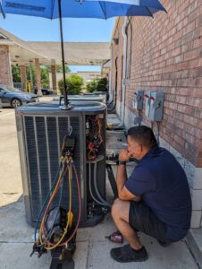 An HVAC technician repairing an outdoor air conditioning unit with gauges at Modern Air Services in Fort Worth, TX.